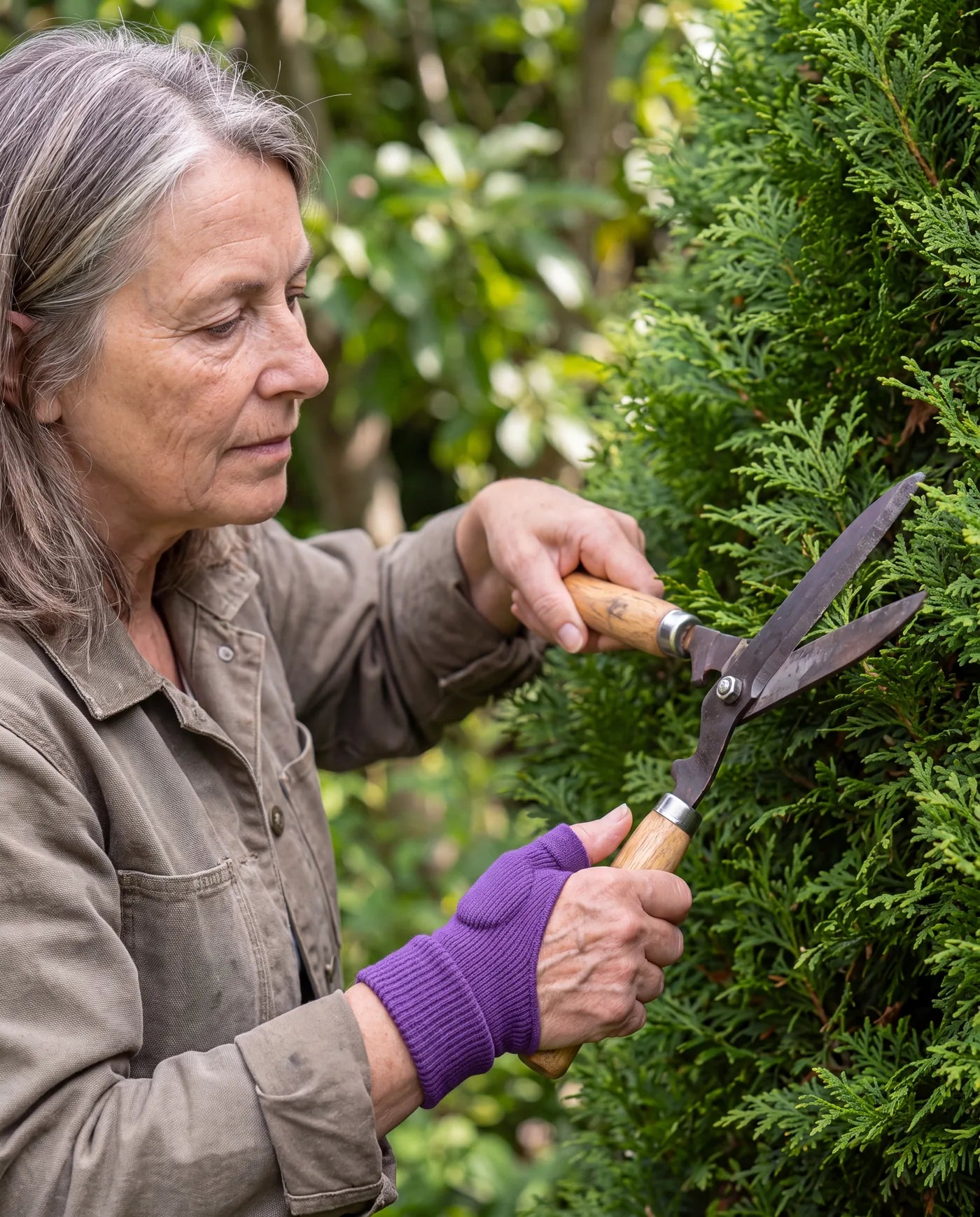 A woman trimming a hedge, wearing the purple Thumb Stabilizer
